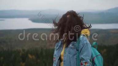 美丽的女人<strong>站在山顶</strong>上，长长的头发随风飘扬，微笑着试图保住她的头发